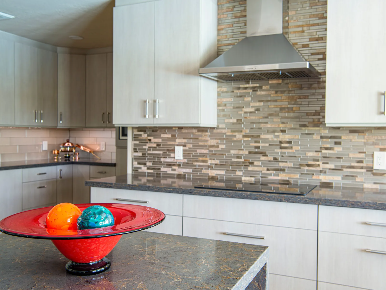 Kitchen with mosaic tile backsplash and stainless hood