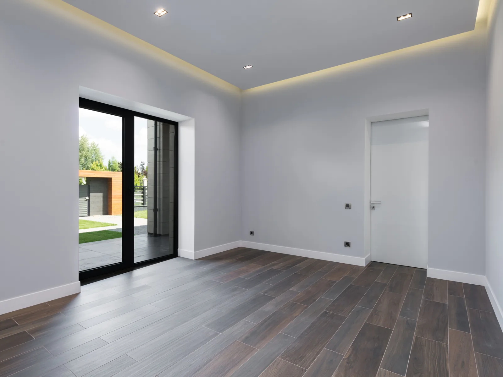Modern room with recessed cove lighting and dark wood floors