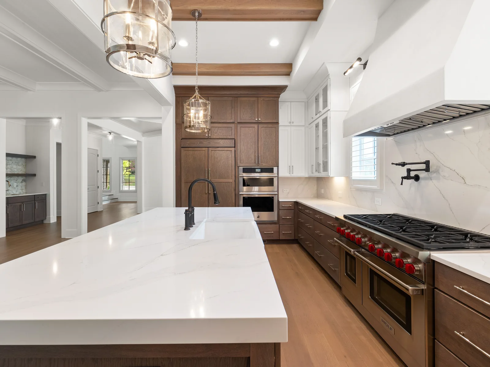 Wood cabinets with white marble island and professional range