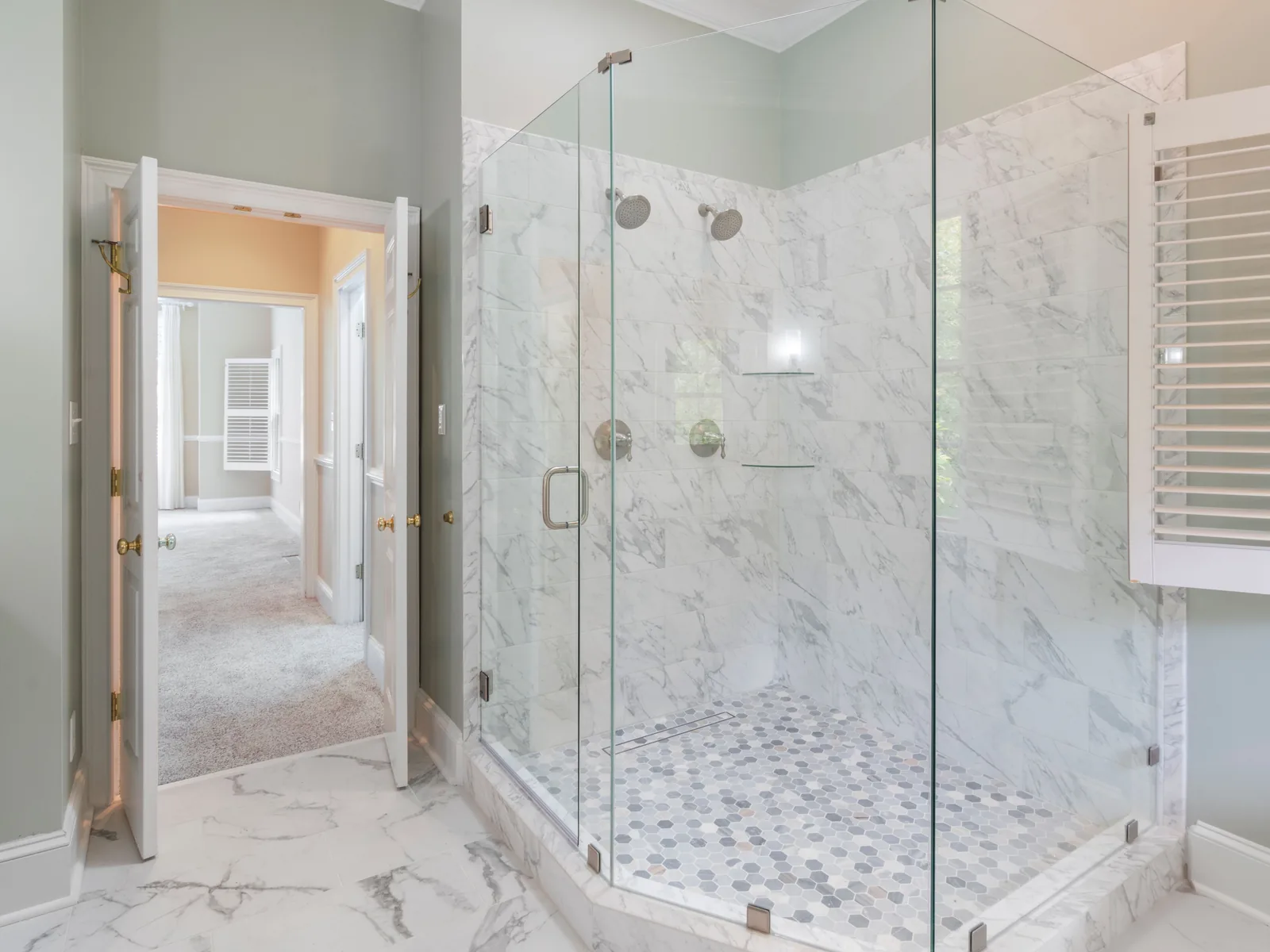 Corner glass shower with marble tile and mosaic floor